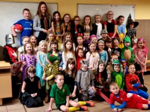 Grupa kilkudziesięciorga dzieci w kolorowych kostiumach na balu przebierańców